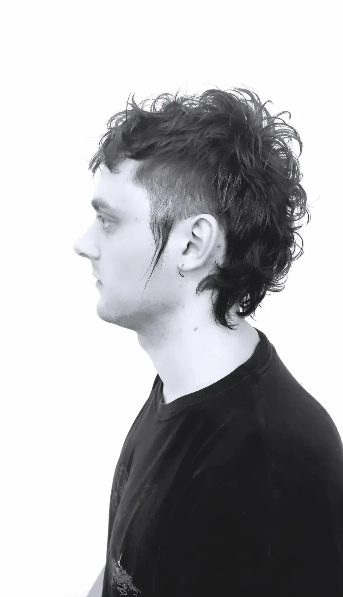 Curly Mullet mit Undercut auf lockigem Haar, Schwarzweißaufnahme im Profil